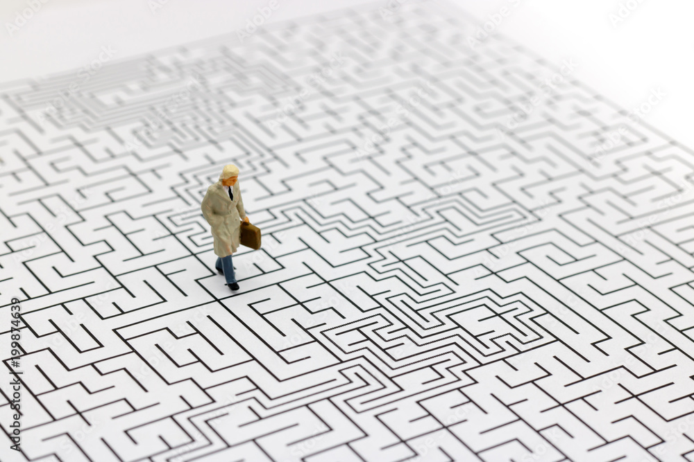 Miniature people: Businessman standing on center of maze. Concepts of finding a solution, problem solving and challenge. Miniature people: Businessman standing on center of maze. Concepts of finding a solution, problem solving and challenge.