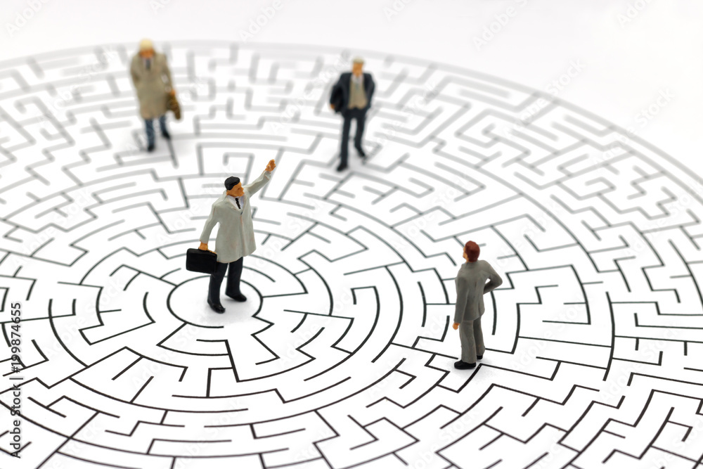 Miniature people: Businessman standing on center of maze. Concepts of finding a solution, problem solving and challenge. Miniature people: Businessman standing on center of maze. Concepts of finding a solution, problem solving and challenge.