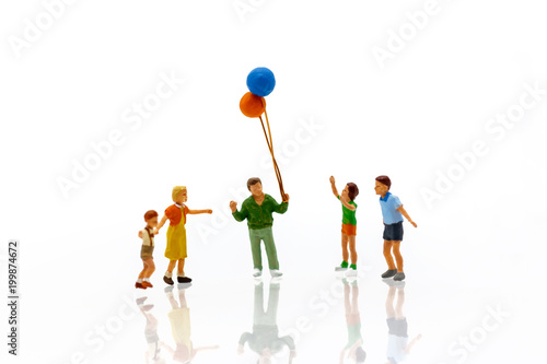 Miniature people children holding balloon with sunlight, happy family day concept.