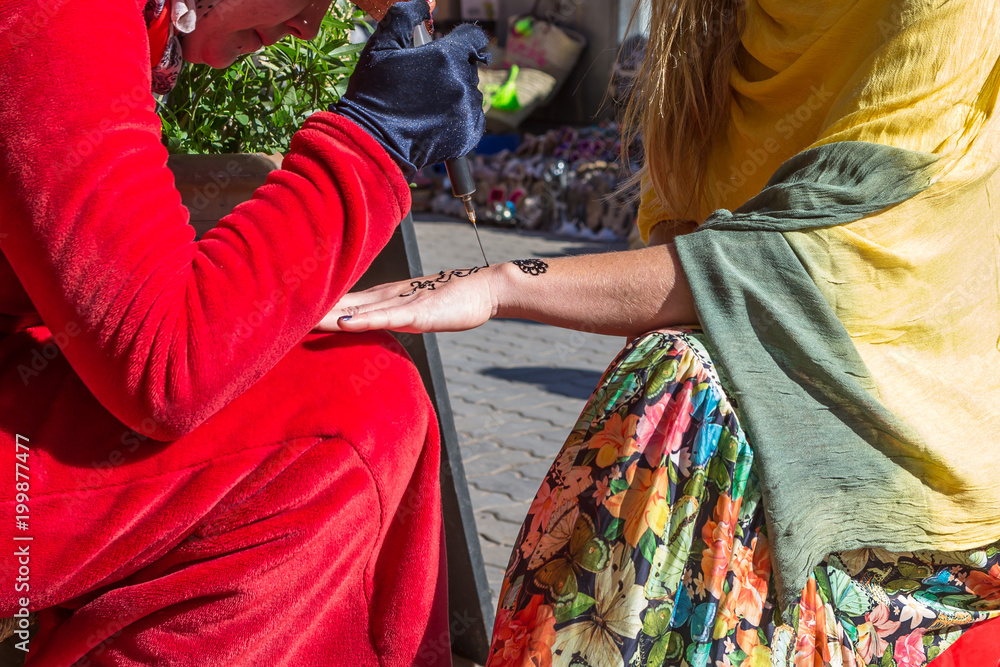 Fototapeta premium A woman making temporary henna tattoo on woman's hand.