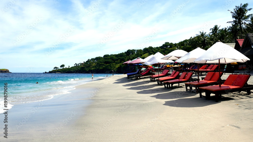 Einsamer Sandstrand am Virgin Beach in Ost-Bali mit Liegen und Sonnenschirmen unter Palmen