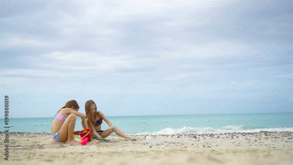 Adorable little girls playing with beach toys during summer vacation on the beach Adorable little girls playing with beach toys during summer vacation on the beach