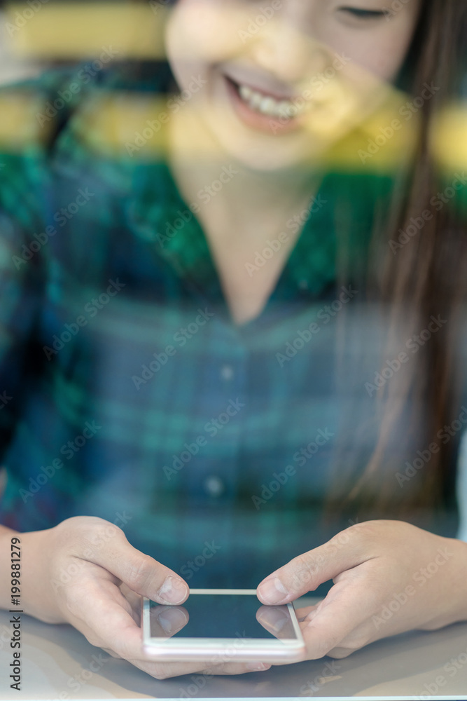 Fototapeta premium Closeup Asian businesswoman hand using the smart mobile phone with happiness action on the desk beside the glass in workplace or co-working space or modern office, business lifestyle concept