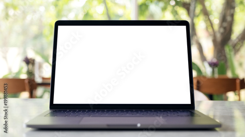 Mockup image of laptop with blank white desktop screen on marble table in modern cafe with nature background