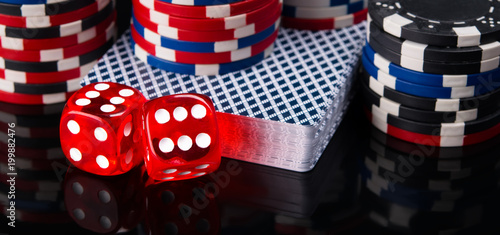two red dice, a deck of cards and poker chips, on a black background