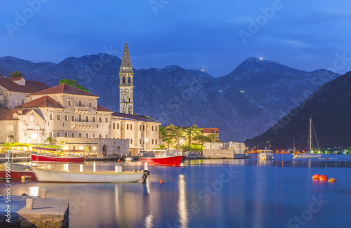 Night panoramic view of Perast old town with famous campanile of St. Nikola Church on the Bay of Kotor in Montenegro, picturesque boats and yachts moorage against Dinaric Alps mountains, Europe photo