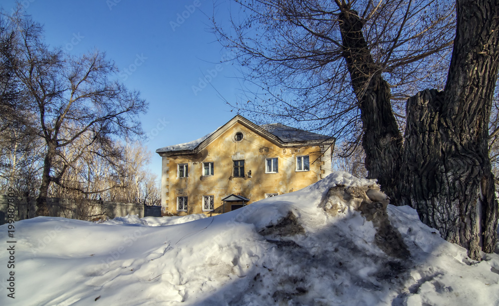 Old house in snow between trees