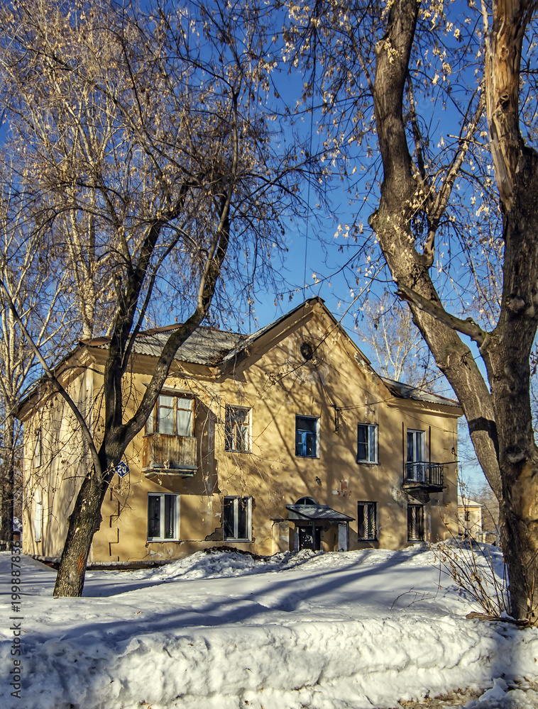 Vertical backdrop with old yellow house in snow between trees