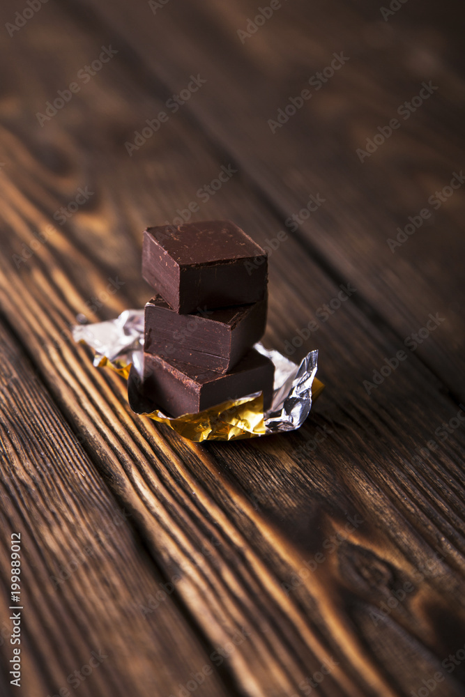pyramid of black chocolate pieces on dark old wooden background pyramid of black chocolate pieces on dark old wooden background