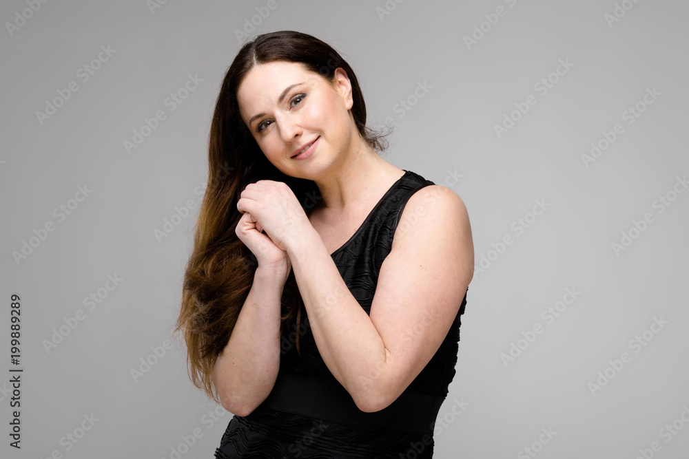 Naklejka premium Attractive young cute positive brunette caucasian smiling business woman in black dress isolated on gray