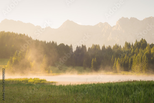Sonnenaufgang mit Nebel über einem See in den Bergen