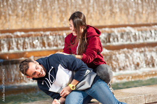 Obraz na plátne Happy couple playing  near a fount in the park.