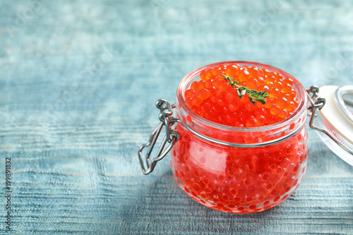 Glass jar with delicious red caviar on table