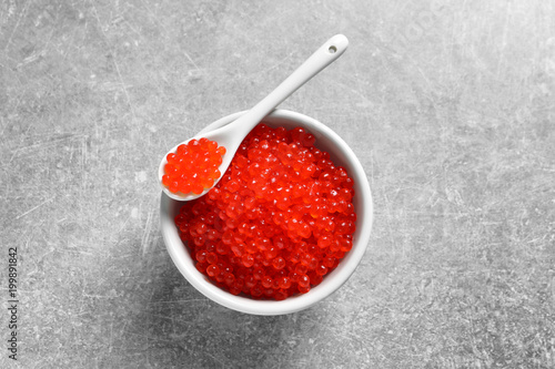 Ceramic bowl and spoon with delicious red caviar on table