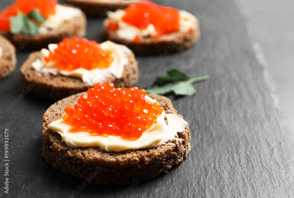 Delicious sandwiches with red caviar on slate plate