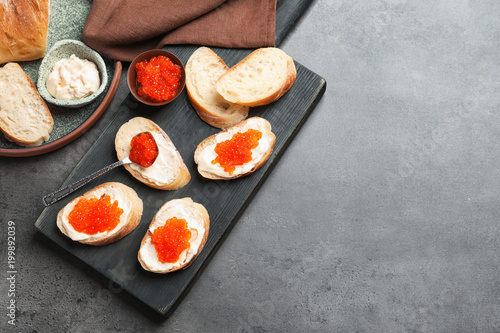Delicious sandwiches with red caviar on wooden board
