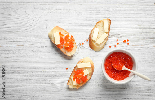 Flat lay composition with red caviar on wooden background