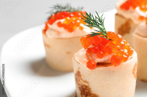 Delicious thin pancakes with red caviar, closeup