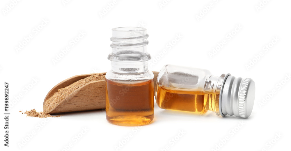 Bottles of cinnamon oil and scoop with powder on white background Bottles of cinnamon oil and scoop with powder on white background
