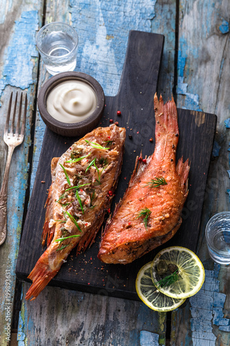 Delicious smoked fish ocean perch on wooden background, top view photo