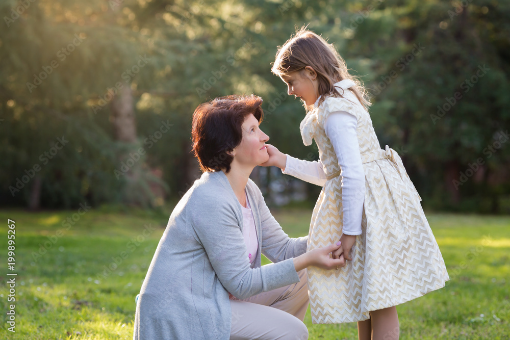 Happy mother and little daughter looking at each other, little girl holding mother's cheek, mother's day concept Happy mother and little daughter looking at each other, little girl holding mother's cheek, mother's day concept