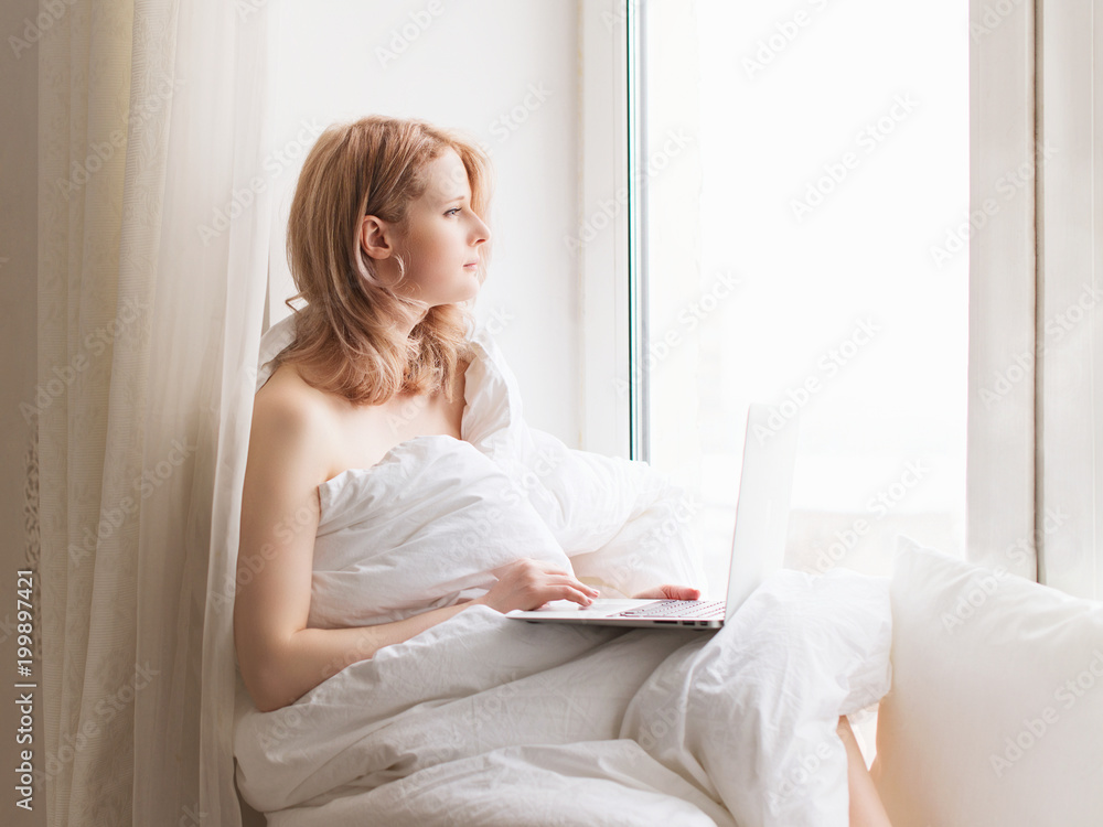 Young pretty woman sitting on window with laptop and working Young pretty woman sitting on window with laptop and working