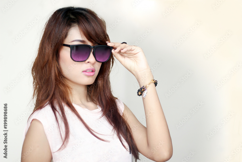 Fototapeta premium Young pretty asian long hair woman wear pink sun glass with gray background.