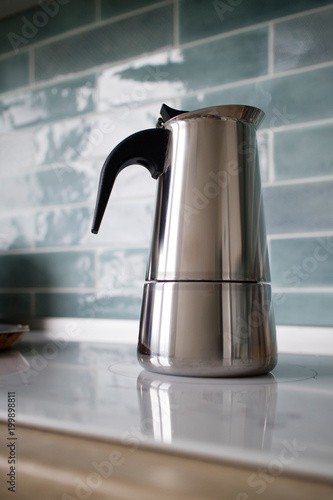 stainless geyser coffee maker on a background of blue tiles