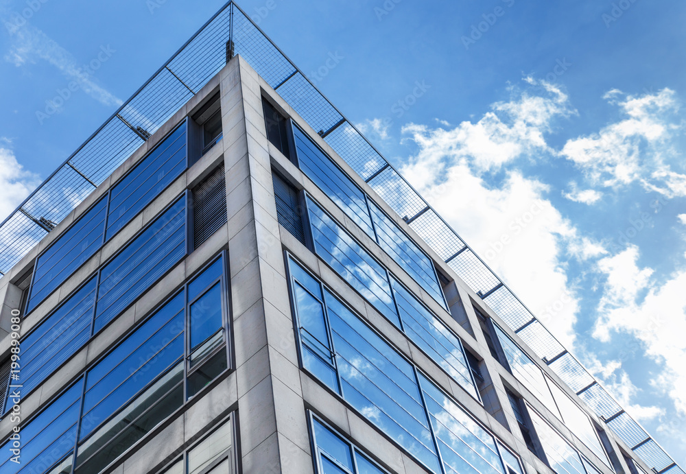 Low angle view of modern building exterior with cloud reflect on glass Low angle view of modern building exterior with cloud reflect on glass