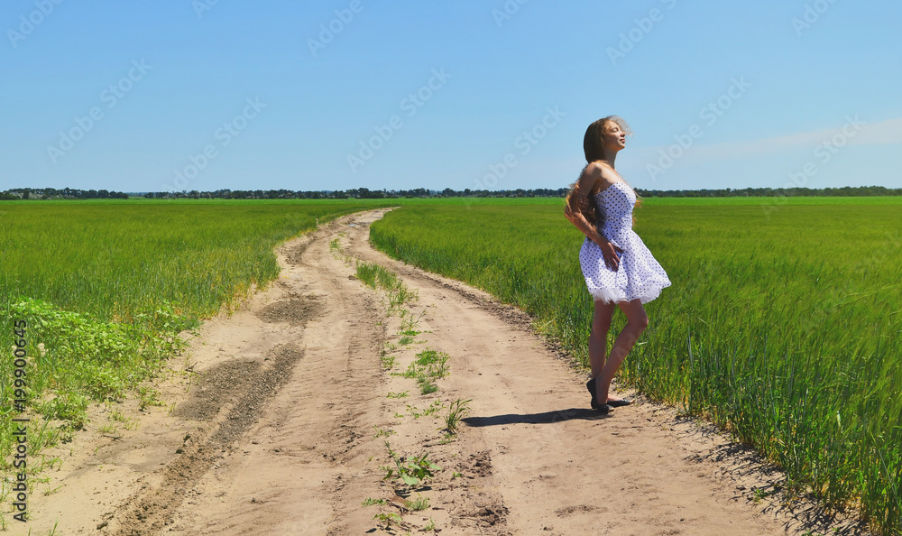 On the road among fields is a young girl