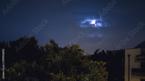 Thunder clouds with lightnings over a tree in an urban area (Padova) 