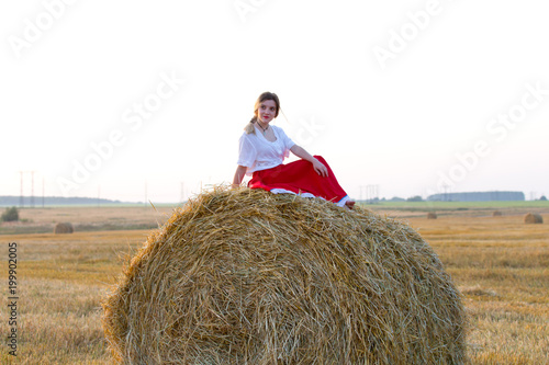 Lovely girl in a traditional costume walks on the field of cereals 