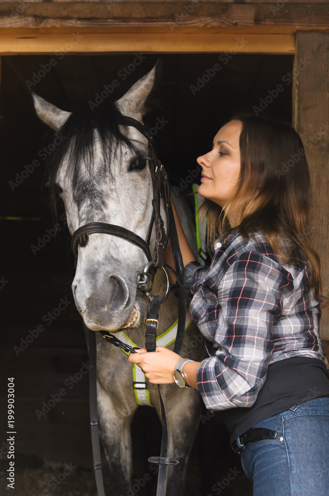 Fototapeta premium girl in plaid shirt with a horse in a stable