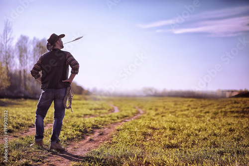 Cowboy standing in a field at sunset © alexkich