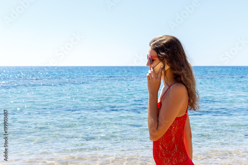 young smiling woman talking by phone on a beach