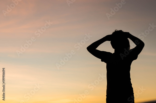 The silhouette of a woman standing looking forward with hope.