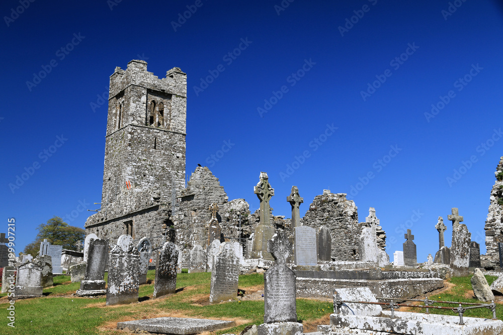 ruiny starego kamiennego średniowiecznego klasztoru i cmentarza w stylu romańskim w irlandii na tle niebieskiego nieba