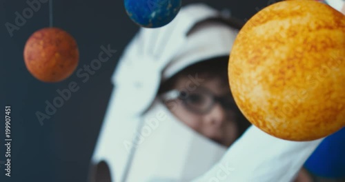 CU Cute little boy wearing cardboard astronaut helmet flying toy rocket through planets, exploring deep space. 4K UHD 60 FPS SLOW MO