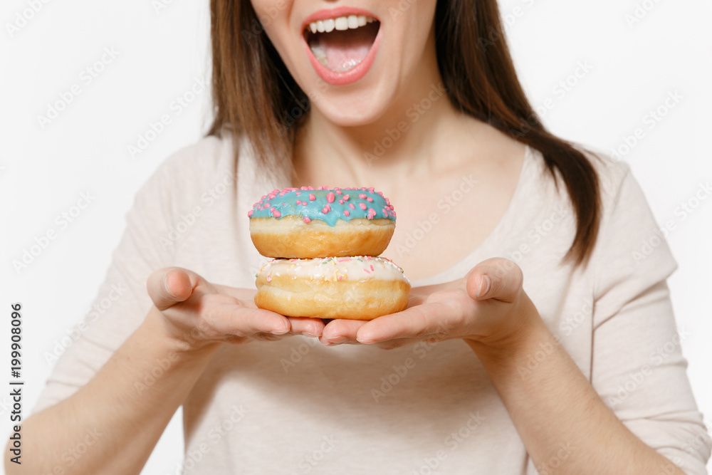 Close up cropped shot woman holding in hands colorful donuts, trying to eat isolated on white background. Proper nutrition or sweets, dessert fast food. dieting concept. Copy space to advertisement. Close up cropped shot woman holding in hands colorful donuts, trying to eat isolated on white background. Proper nutrition or sweets, dessert fast food. dieting concept. Copy space to advertisement.
