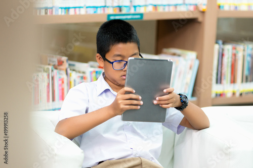 Asian student is searching for knowledge with tablet in the library.