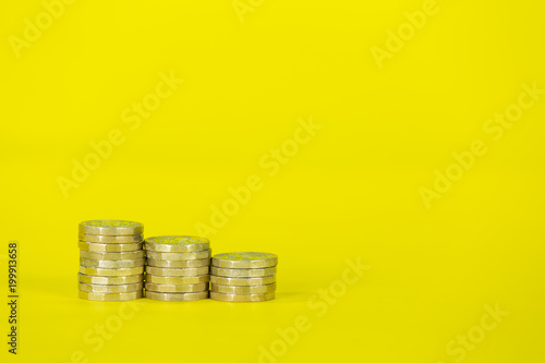 Stacks of Pound Coins on a Yellow Background