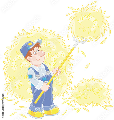 Smiling farmer tedding hay with a pitchfork in a hayloft