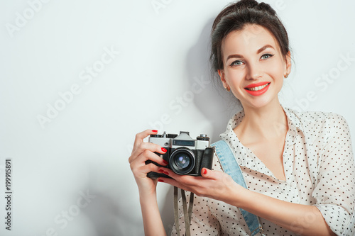 Fashion look, pretty cool young woman model with retro camera wearing in denim clothes posing on white wall. Expressive beauty girl photographer holding photocam. Emotions Lifestyle People concepts photo