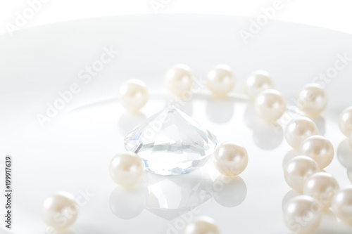 Luxury concept.  White pearl and one diamond in a plate