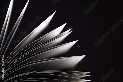 Black and white. Macro view of book pages. Concept of open book, white sheets on dark black background. Education background. Copy space for text. Close-up, selective focus
