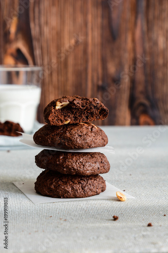 Chocolate cookies for breakfast with hazelnut and a glass of milk on a gray table.