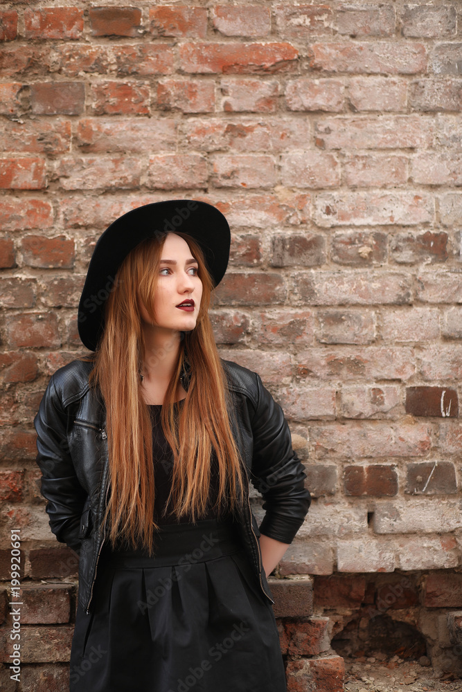 A girl walks down the city street in a leather waistcoat with a A girl walks down the city street in a leather waistcoat with a
