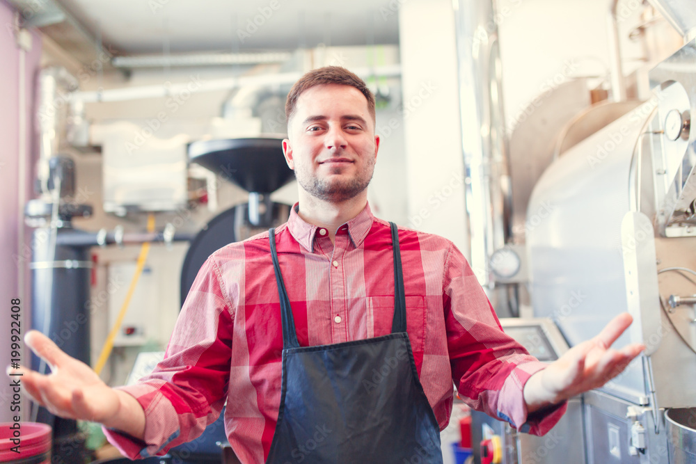 Picture of happy barista man in apron on background of industrial coffee grinder Picture of happy barista man in apron on background of industrial coffee grinder