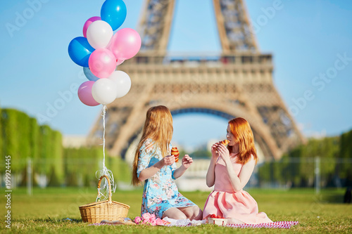 Two young women having picnic near the Eiffel tower in Paris, France photo