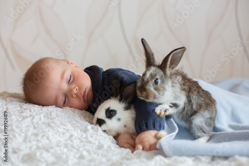 Cute little baby boy  sleeping with pet rabbits